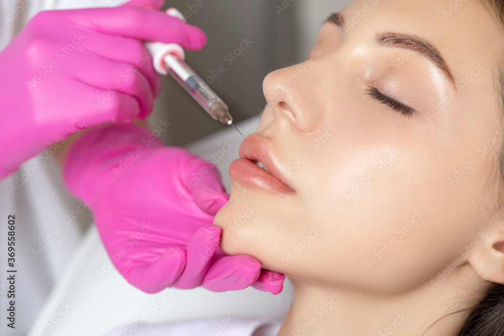 Woman with beautiful clean skin. Cosmetologist does injections for lips augmentation and anti wrinkle of a beautiful woman. Women's cosmetology in the beauty salon. Woman with beautiful clean skin. Cosmetologist does injections for lips augmentation and anti wrinkle of a beautiful woman. Women's cosmetology in the beauty salon.