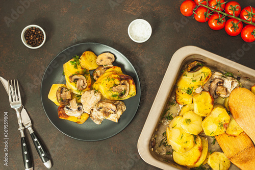 Potato wedges baked with mushrooms, herb oven roasted, with thyme, a close-up in a baking tray photo