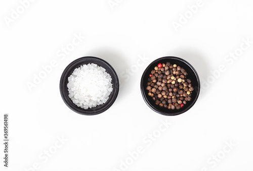 Salt and pepper in black bowl on white background