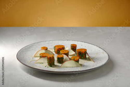 veganes Karotten Rezept mit Äpfeln auf weißem Keramik Teller und weißem Marmor Tisch mit gelbem Hintergrund