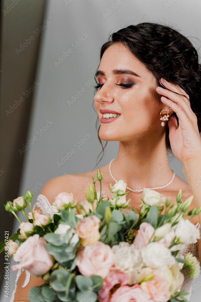 Bride with wedding bouquet smiles and touches her face and hair. Attractive girl portrait for social networks. Girl in wedding gown on blank background. Dreamily bride woman Bride with wedding bouquet smiles and touches her face and hair. Attractive girl portrait for social networks. Girl in wedding gown on blank background. Dreamily bride woman