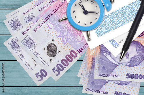 50000 Romanian leu bills and alarm clock with pen and envelopes. Tax season concept, payment deadline for credit or loan. Financial operations using postal service photo