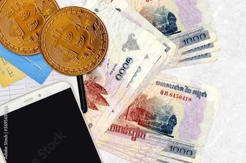 1000 Cambodian riels bills and golden bitcoins with smartphone and credit cards. Cryptocurrency investment concept. Crypto mining or trading photo