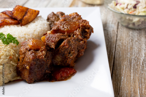 A view of a plate of Caribbean style oxtail, in a restaurant or kitchen setting.