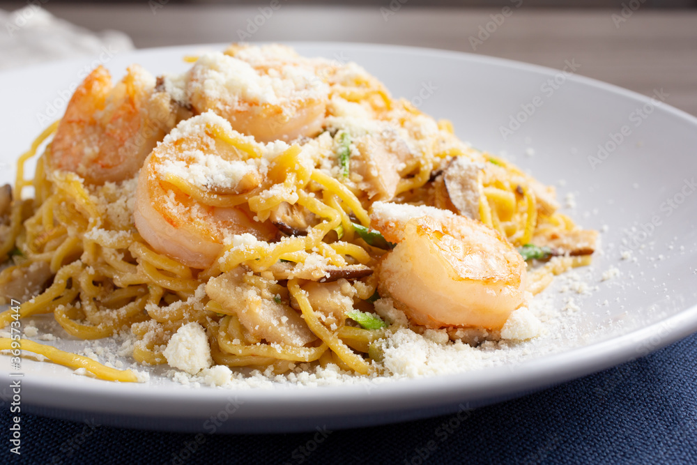 A view of a plate of spicy garlic noodles, in a restaurant or kitchen setting.
