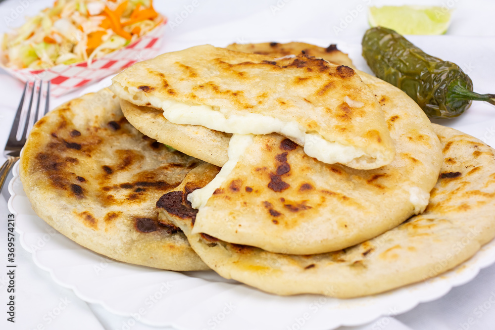 A view of a stack of pupusas, in a restaurant or kitchen setting.