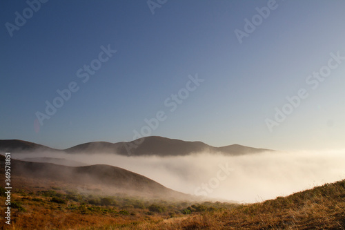 Misty clouds cover distant mountains with fog. Looking east in the morning from Point Mugu State Park's trail.