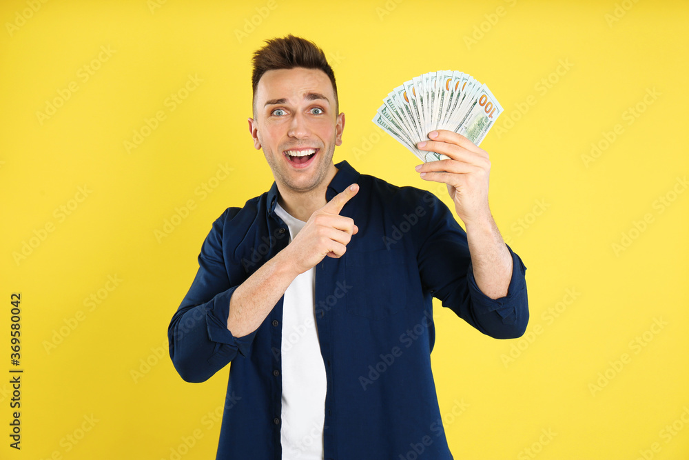 Emotional man with cash money on yellow background Emotional man with cash money on yellow background