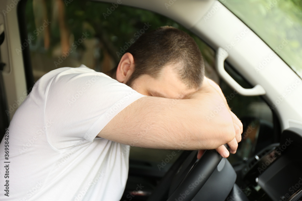 Tired man sleeping on steering wheel in his car Tired man sleeping on steering wheel in his car
