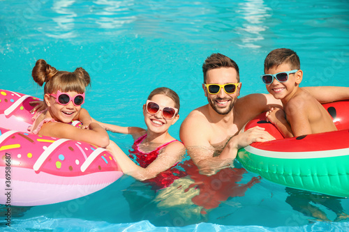 Happy family with inflatable rings in swimming pool