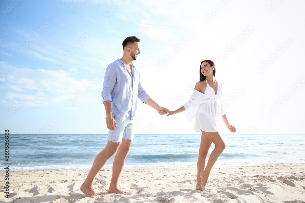 Happy young couple holding hands on beach