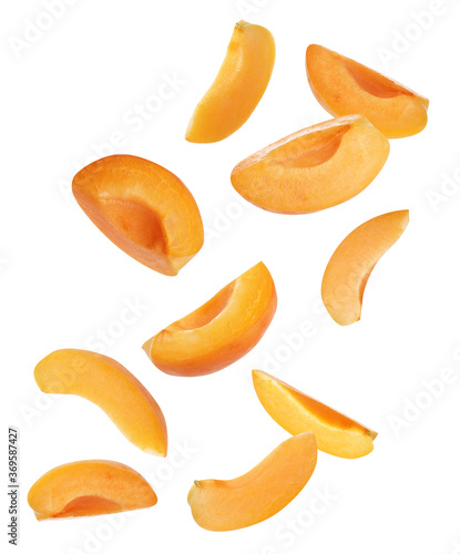 Ripe apricot slices falling on white background