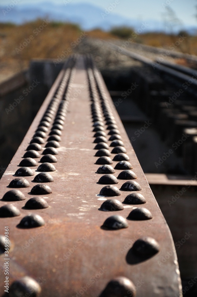 Vertical closeup of and old railway steel bridge in the foreground and mountains in the background Vertical closeup of and old railway steel bridge in the foreground and mountains in the background