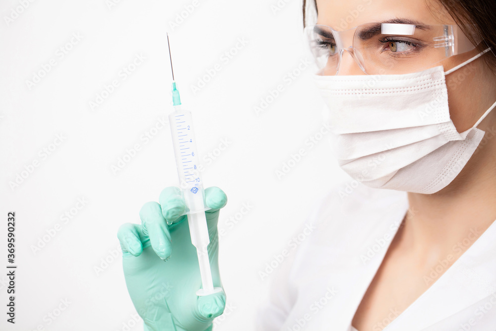 Woman doctor in medical mask picks up syringe to give an injection. Woman doctor in medical mask picks up syringe to give an injection.