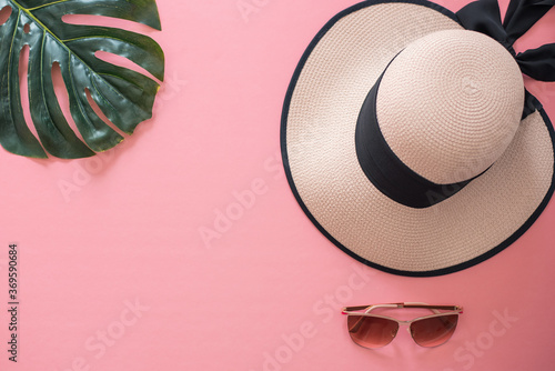 Straw hat and sunglasses on a pink background with space for copy