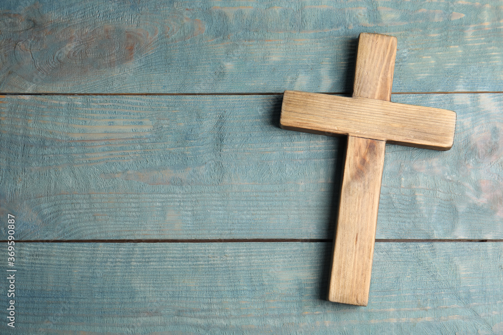 Christian cross on light blue wooden background, top view with space for text. Religion concept
