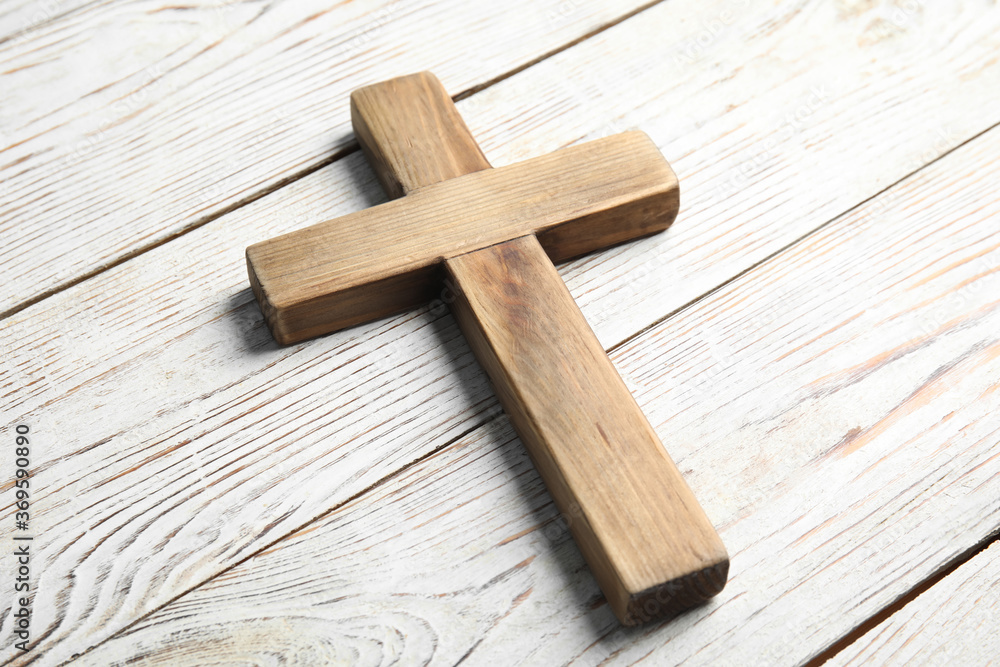 Christian cross on white wooden background, closeup. Religion concept