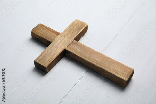 Christian cross on white wooden background, closeup. Religion concept