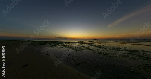 Time lapse: Sunset view on the ocean with reflection and silhouette. A beached foreground log adds interest. Slow motion timelapse 4K footage. Shot at 2160p.