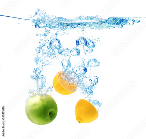 Apple and lemon falling down into clear water against white background