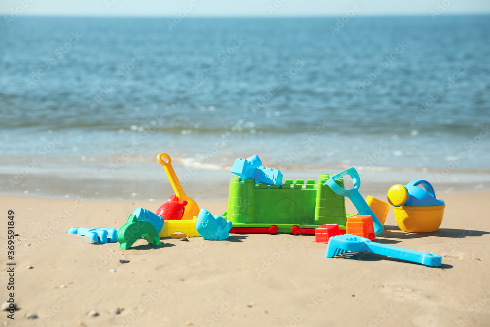 Different child plastic toys on sandy beach. Space for text Different child plastic toys on sandy beach. Space for text