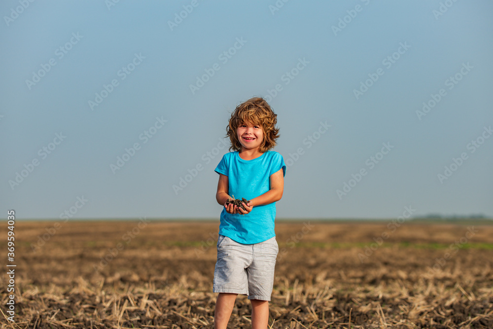 Cute child on the black soil background. Soils and fertilizers.