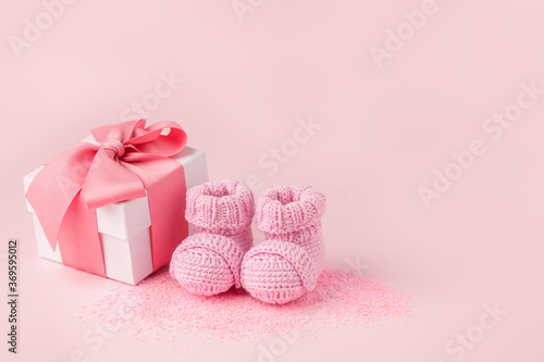 Pair of small pink baby socks and gift box on pink background with copy space for your warm message, baby shower, first newborn party background, copy space, monochrome