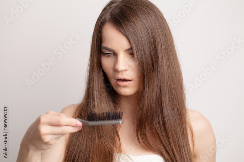 Very upset young woman with comb and problem loss hair.