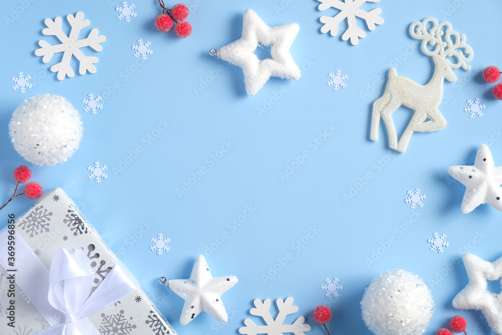 Christmas composition. Flat lay white snowflakes, gift box, Rudolph reindeer, confetti stars, red berries on blue background. Frame of Christmas decorations. Top view, copy space. Christmas composition. Flat lay white snowflakes, gift box, Rudolph reindeer, confetti stars, red berries on blue background. Frame of Christmas decorations. Top view, copy space.