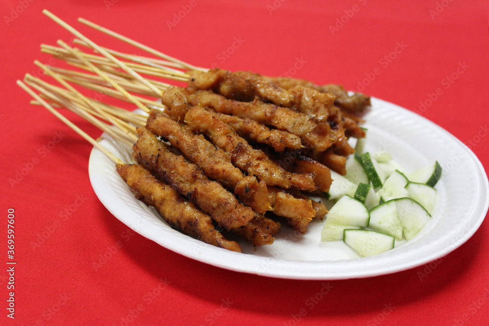 Satay or sate, skewered and grilled meat, served with cucumber. Traditional Malay food in Malaysia, Singapore and Indonesia Satay or sate, skewered and grilled meat, served with cucumber. Traditional Malay food in Malaysia, Singapore and Indonesia