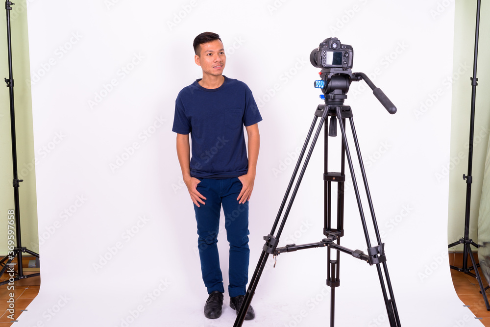 Portrait of happy young Asian man with camera