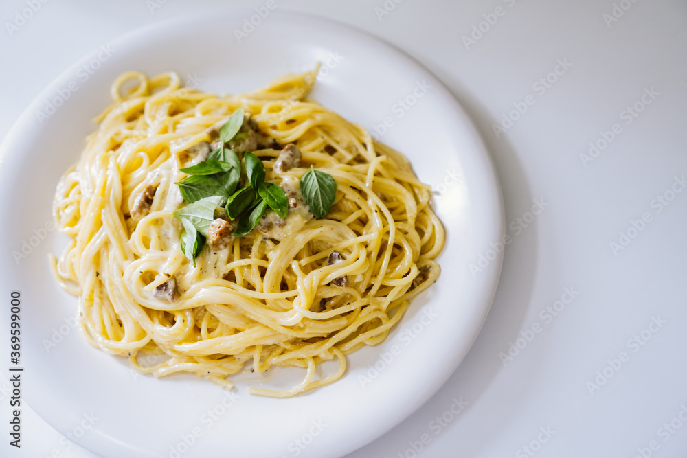 Homemade spaghetti Carbonara with pieces of bacon and basil.