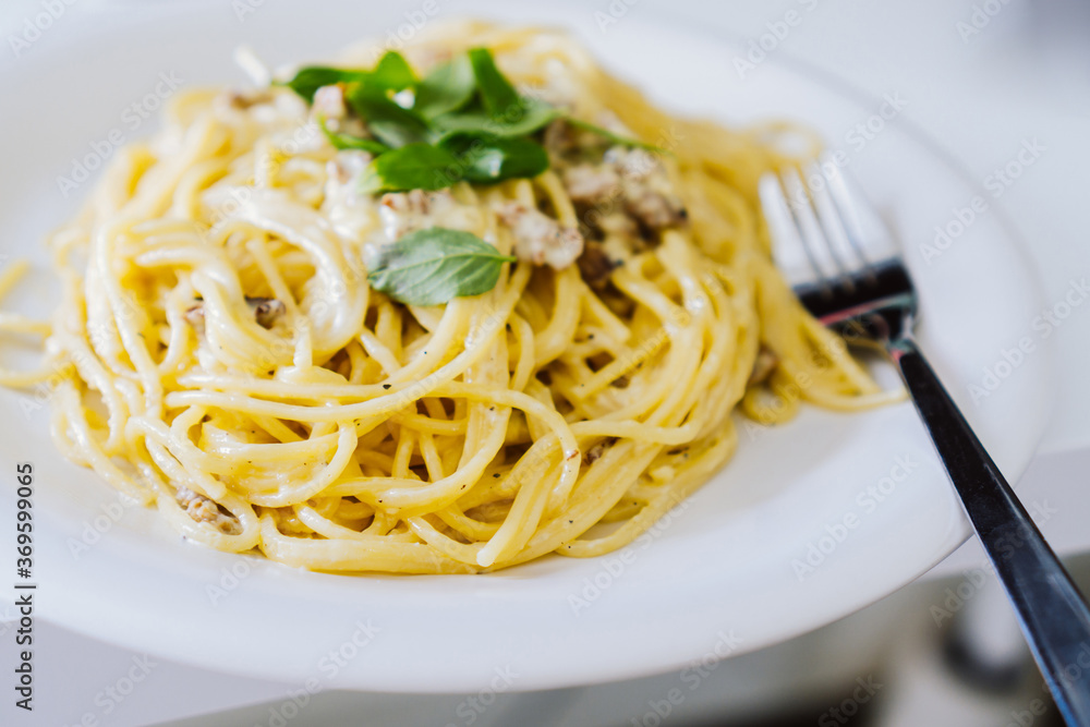 Homemade spaghetti Carbonara with pieces of bacon and basil. Fork on the side Homemade spaghetti Carbonara with pieces of bacon and basil. Fork on the side