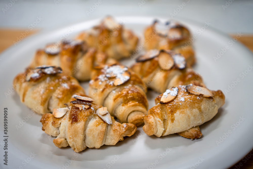 Freshly baked homemade little croissants with almond and sugar powder on a white plate