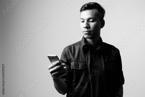 Portrait of young Asian businessman using phone in black and white