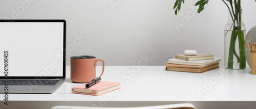 Workspace with laptop, stationery, mug, books, decoration and copy space on white table, clipping path.