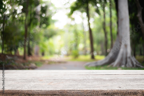 Empty wooden desk space and blurry background of garden or park for product display montage.