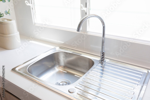 stainless steel kitchen sink detail on white granite worktop at home
