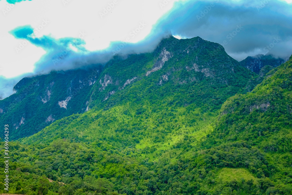 Mountains with green trees and cloud-covered peaks.