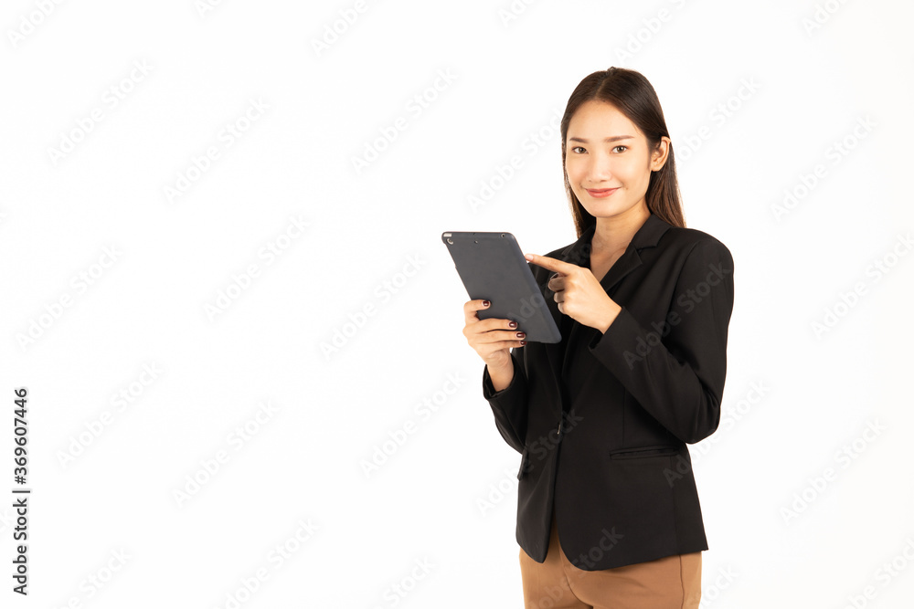 An asian business womanin a black suit stands smiling using the taplat look at the camera ,isolated on white background. An asian business womanin a black suit stands smiling using the taplat look at the camera ,isolated on white background.