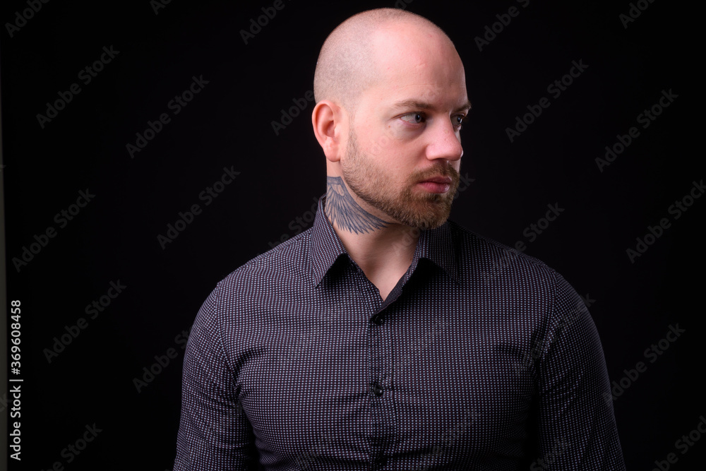 Handsome bald bearded businessman against black background