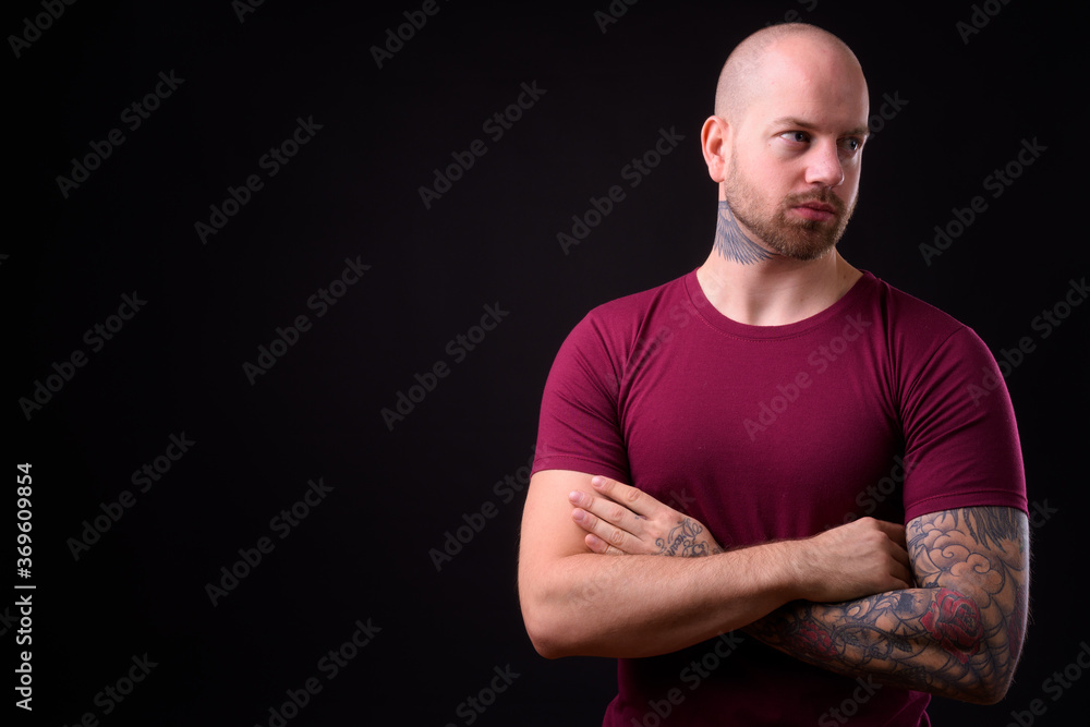 Handsome bald bearded man against black background Handsome bald bearded man against black background