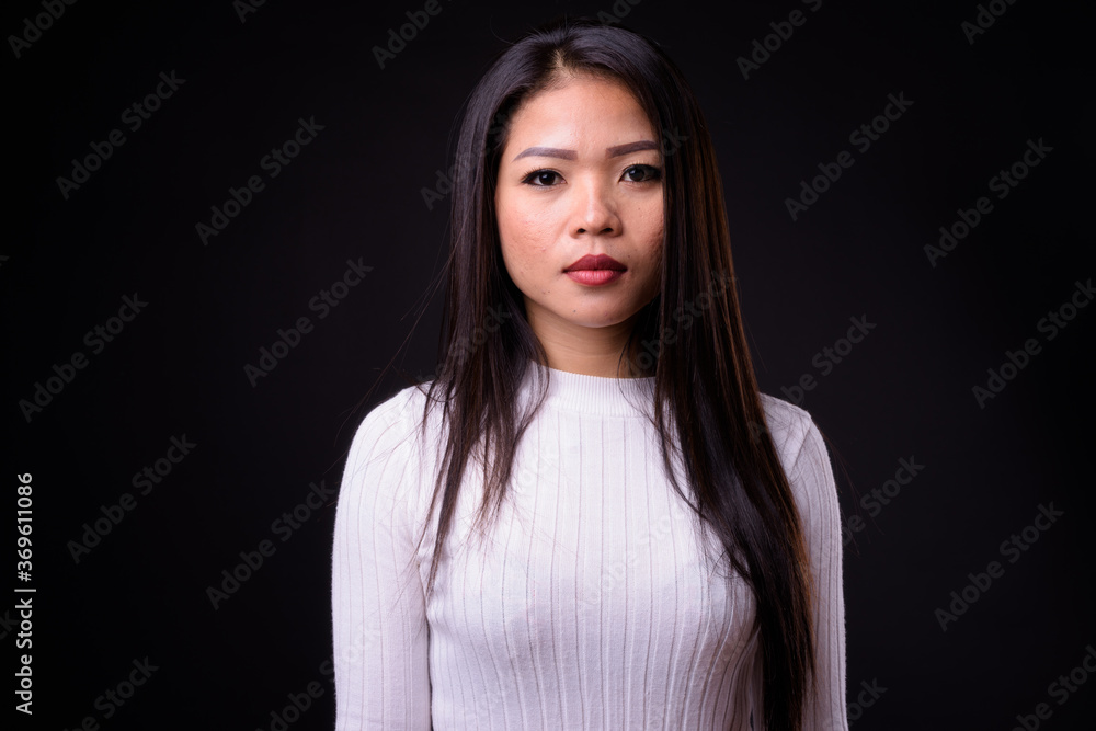 Portrait of young beautiful Asian woman against black background Portrait of young beautiful Asian woman against black background