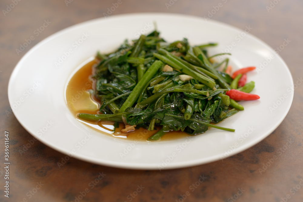 Stir fried water spinach on wooden table