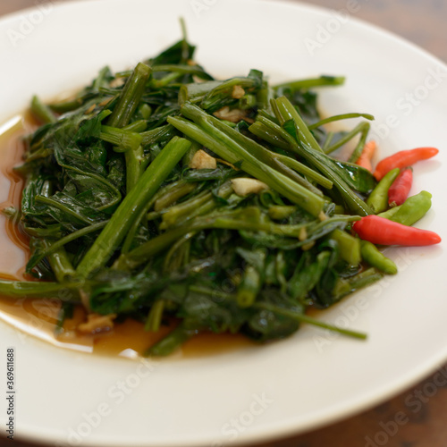 Stir fried water spinach on wooden table