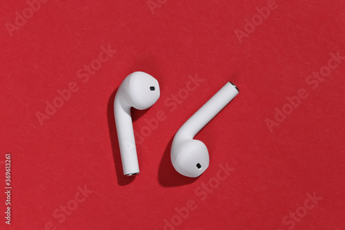 White true wireless bluetooth headphones or earbuds on bright red background