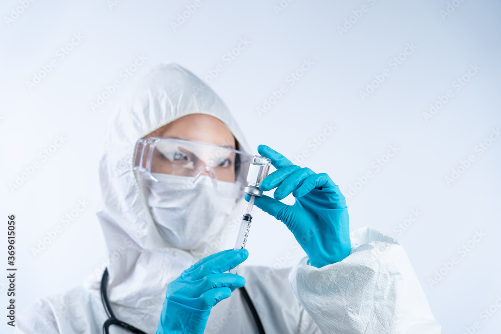 Female doctor in PPE (personal protective equipment), gloves face mask and safety glasses holding coronavirus vaccine bottle and needle. Female doctor in PPE (personal protective equipment), gloves face mask and safety glasses holding coronavirus vaccine bottle and needle.