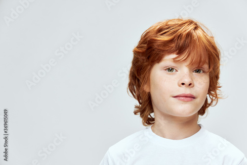 Cute redhead boy cropped view white t-shirt freckles on face close-up 