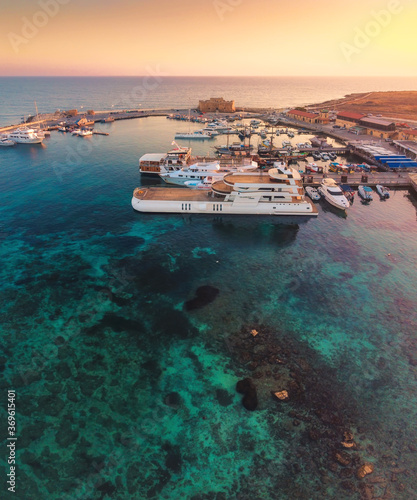 Beautiful aerial sunset shot of Paphos Castle and Paphos Harbor in Cyprus. Crystal clear water, fishing boats, luxury yachts - amazing travel destination for all year vacation.  photo