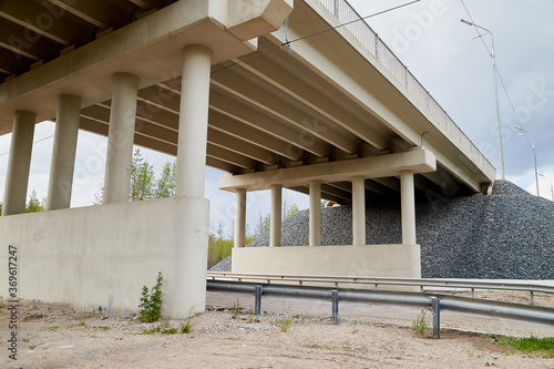 Bottom view of the prestressed concrete beams and piers of bridge crossing many-lane expressway of road.